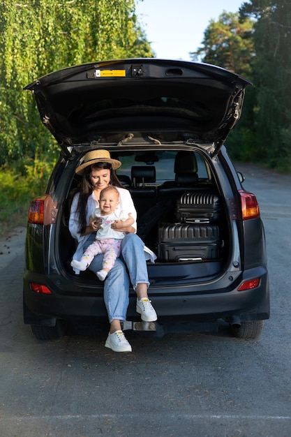 Car journey Travel with a child by car Mother and daughter sit in a car with an open trunk