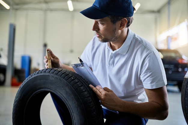 Car mechanic checking depth of a tire in auto repair shop