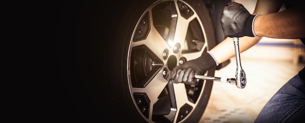 Car mechanic checking and use a wrench to change the tire Concept of car care service maintenance and safety