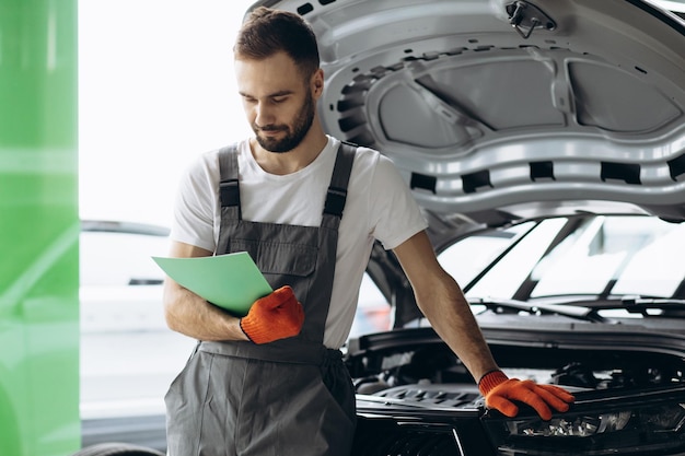 Car mechanic holding documents and checking car