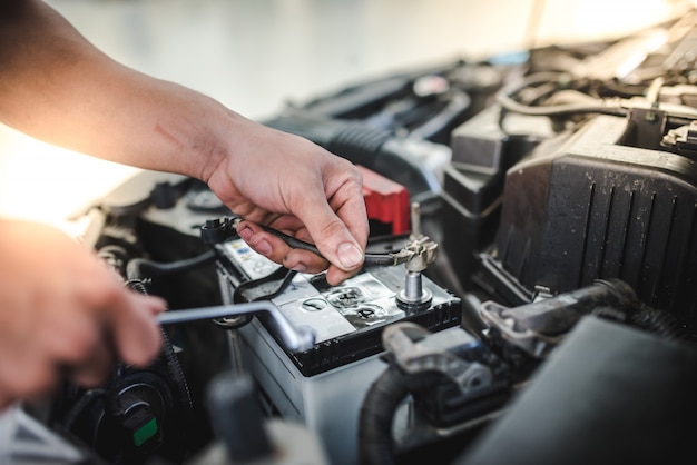 The car mechanic is about to remove the battery to replace the new battery of the car in the car repair shop.