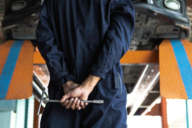 Car mechanic looking to the engine in the garage. Service Car motor repair.