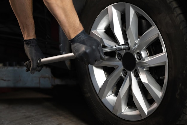 Car mechanic replacing a car wheel tire in garage workshop auto service repairman mounting wheel