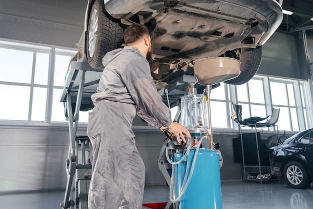 Car Mechanic Replacing Oil in Motor Engine. Auto service shop