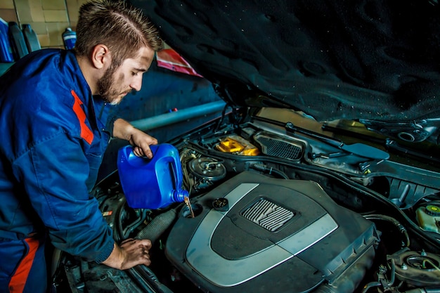 Car mechanic replacing and pouring oil into engine at maintenance repair service station. 