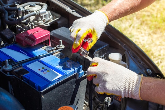 The car mechanic unscrews the car battery holder to repair or replace it. Transport service.