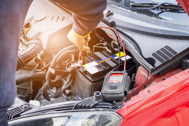 Car mechanic use voltmeter to check car battery voltage level