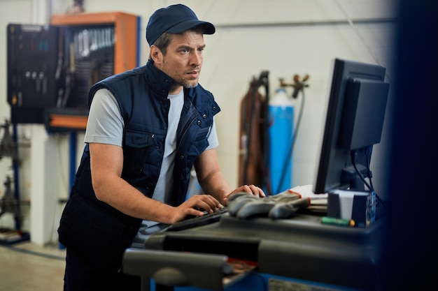 Car mechanic using computer while working at auto repair shop