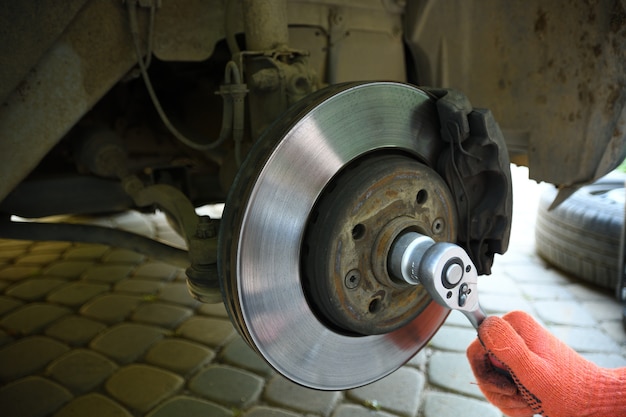 car mechanic worker repairing suspension of lifted automobile at auto repair garage shop station