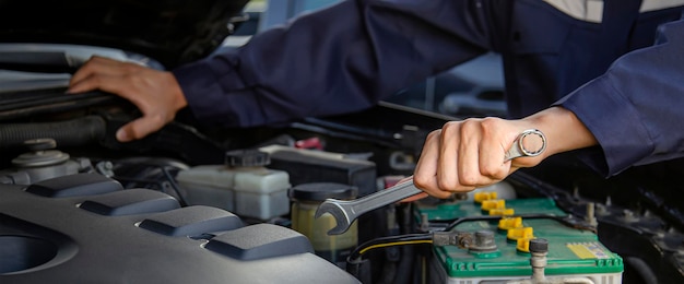 Car mechanic working on car engine, car maintenance concept.