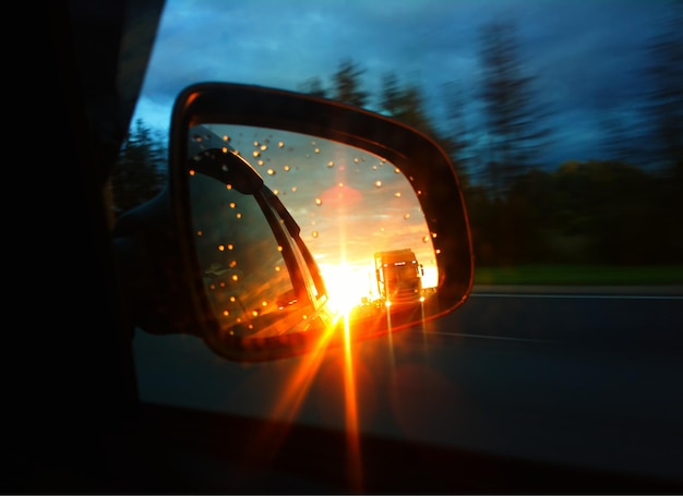 Car mirror of rear view during dramatic sunset background