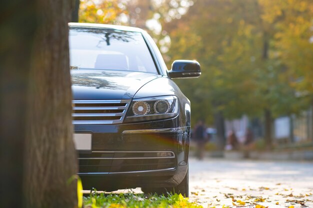 car parked on a city street side on autumn day with blurred people walking in pedestrian zone.