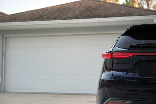 Car parked in front of wide garage double door on concrete driveway of new modern american house