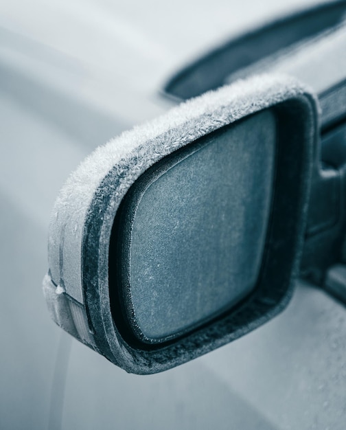 Car parked outside during the winter season Macro shot of a side view mirror is covered with a thin layer of ice Frosty morning