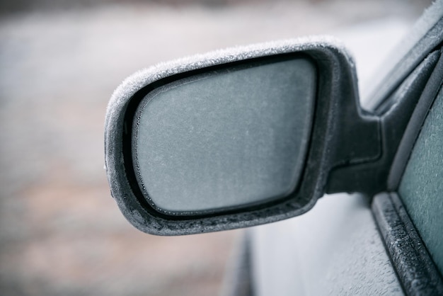 Car parked outside during the winter season Macro shot of a side view mirror is covered with a thin layer of ice Frosty morning