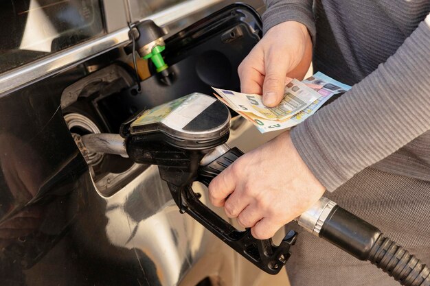 Car refuelling on petrol station Man refilling car with fuel and holding money euros Close up Gasoline diesel is getting more expensive Petrol industry and service Petrol price and oil crisis