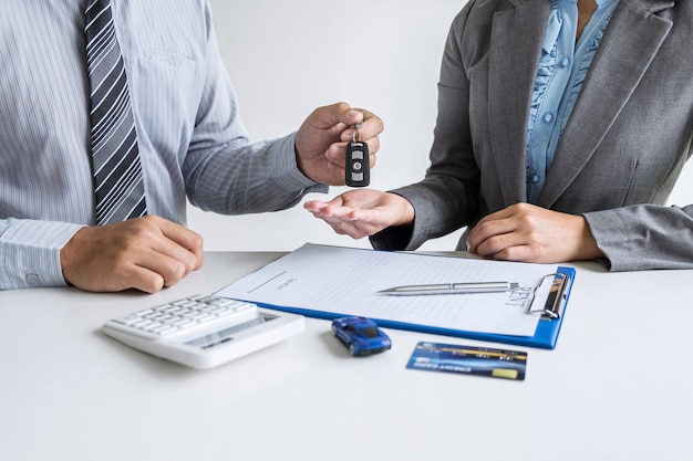 Car rent agent giving the key to a new car to a client