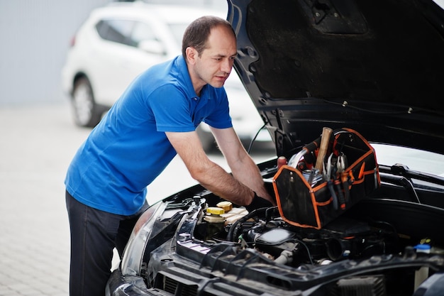 Car repair and maintenance theme Mechanic in uniform working in auto service checking engine