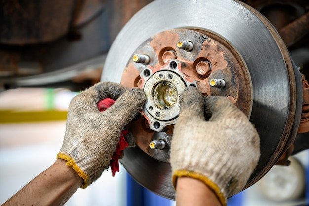 Photo car repair service mechanic is putting lubricating grease into bearings and assembling new car bearings. car mechanic inspecting the undercarriage in industrial plants