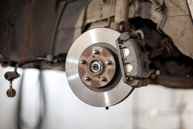 A car's brake caliper is hanging from a car's suspension Disc brake of the vehicle for repair