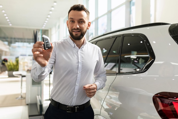 The car seller hands over the keys to the new suv to the buyer in the car dealership