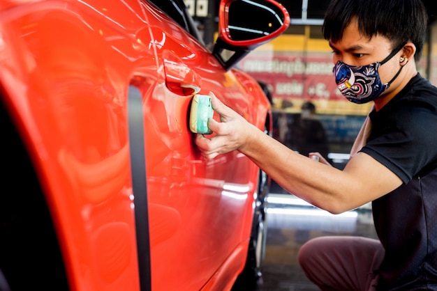 Photo car service worker applying nano coating on a car detail