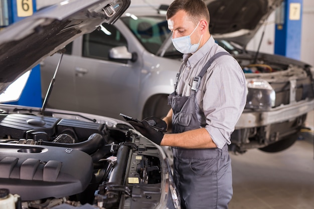 Car service worker carries out diagnostics and car repairs in the room.