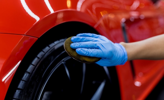 Photo car service worker polishing car wheels with microfiber cloth