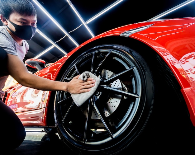 Car service worker polishing car wheels with microfiber cloth.