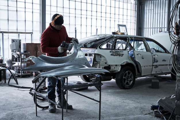 Car service worker repairs restores car