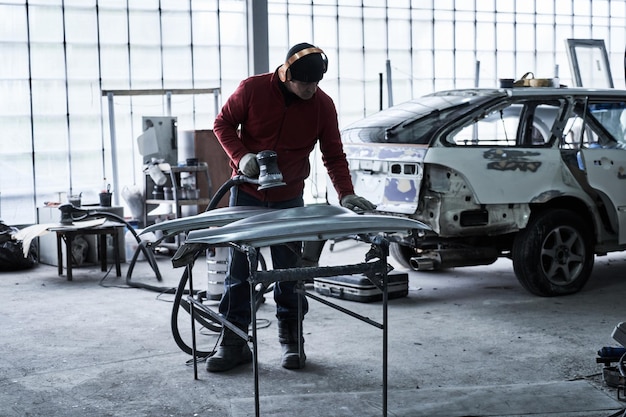 Car service worker repairs restores car