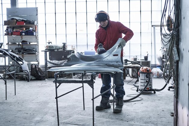 Car service worker repairs restores car