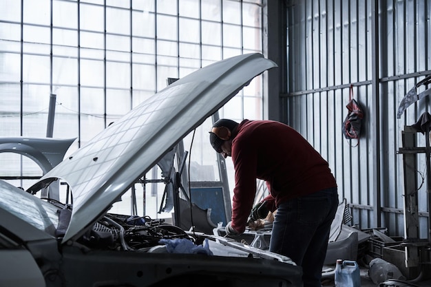 Photo car service worker repairs restores car