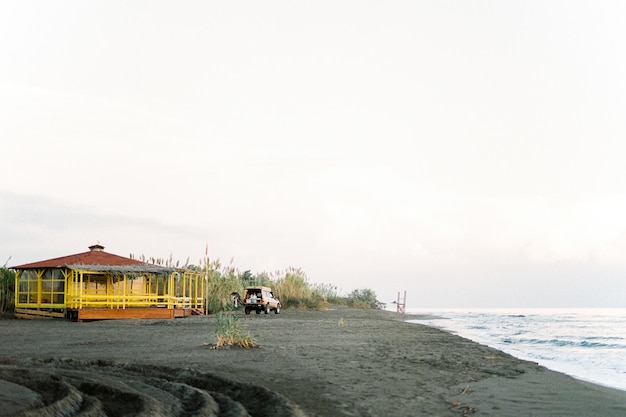 Car stands near a wooden house on the beach by the sea