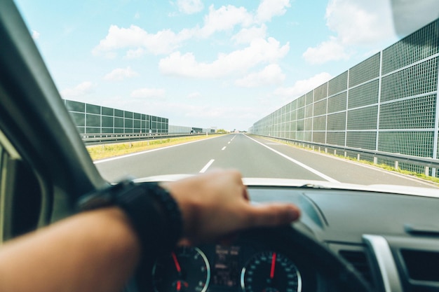 Car travel concept man hand on steering wheel speedway