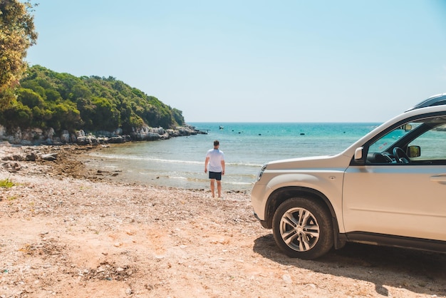 Car travel concept man at summer beach looking at sea