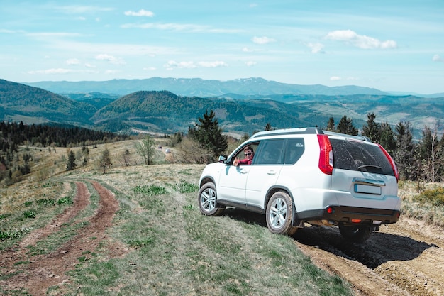 Car travel concept suv driving by country road leading to the mountains summer sunny day