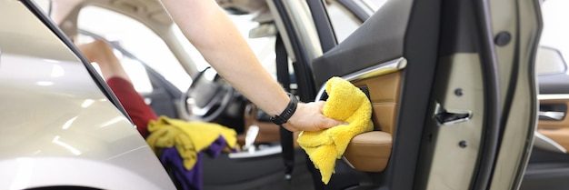 Car wash service worker wipes car door with rag wipes washing and drying car with dry trim