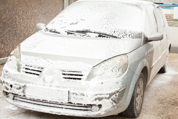 Car wash with foam in car wash station Carwash Washing machine at the station Car washing concept Car in foam