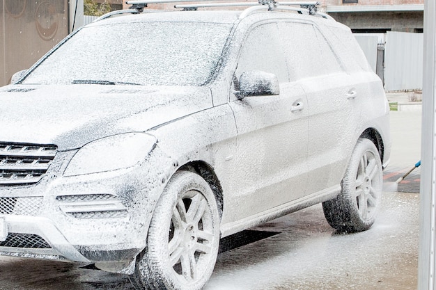 Car wash with foam in car wash station. Carwash. Washing machine at the station. Car washing concept. Car in foam