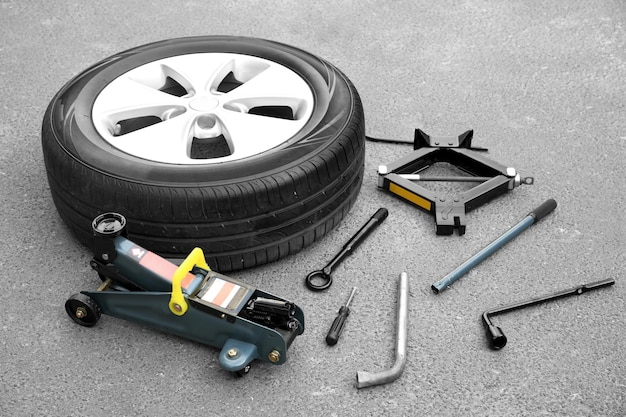 Car wheel with tools on asphalt background