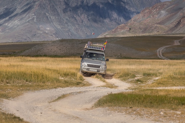 Car with German and Mongolian flags on winding road in the Altai Mountains of Mongolia