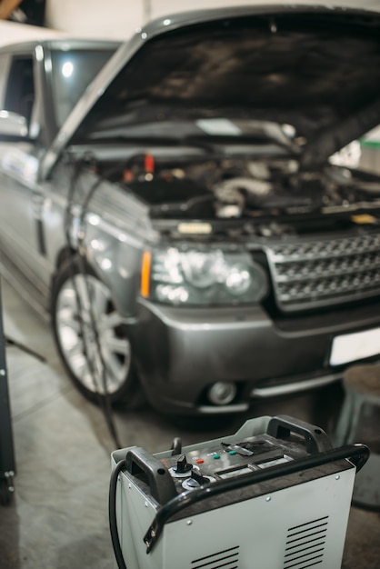 Car with opened hood and charging station