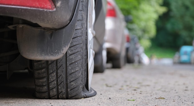 Car with punctured flat tire parked on roadside