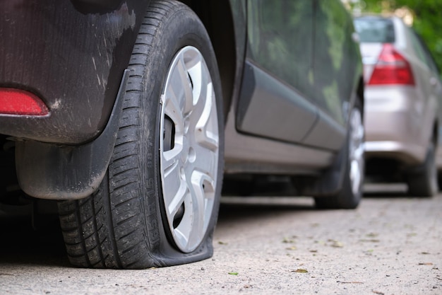 Car with punctured flat tire parked on roadside