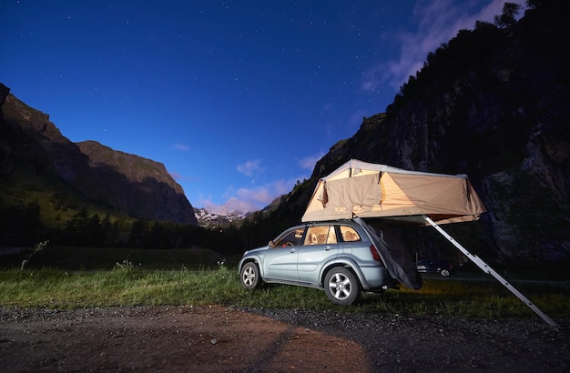 Car with rooftop camping tent in mountains