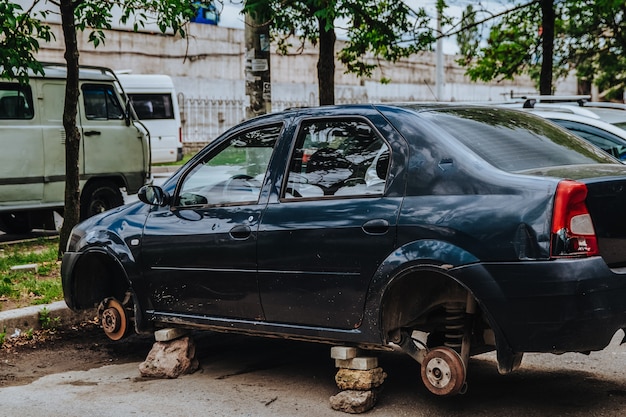 A car without wheels is on the street the thieves used stones to park the car vandalism