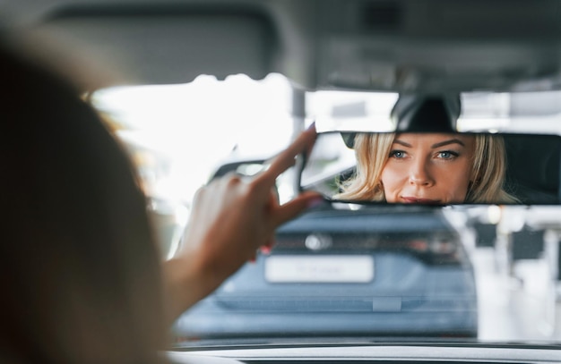 In the car Woman in formal clothes is indoors in the autosalon