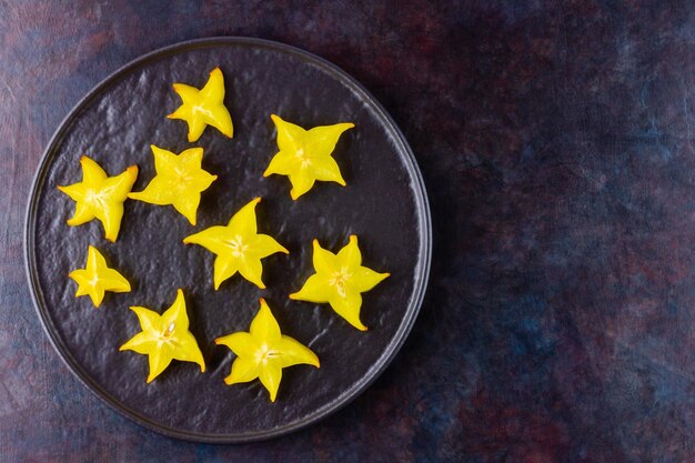 Carambola on black plate Sliced fresh carambola on dark background Top view Copy space