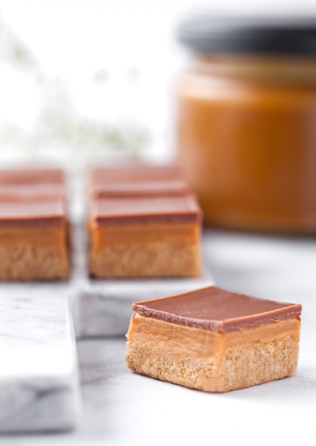 Caramel and biscuit shortcake bites dessert on marble board with jar of salted caramel